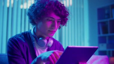 Man, Tablet Kullanarak Koltuğa Rahatlar, Muhtemelen Okuma ve Yayınlama İçeriğini İzler. Günlük Kişisel Bakım ve Dijital Çağ 'da Yavaş Yaşam. Dijital Detox, Akıl Sağlığı, Odaklanma Kipi.