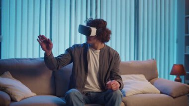 Genç Adam, AR Gözlükleriyle Sanal Arayüz 'le Gece Masasında Oturuyor. Yarının Dijital Dünyası 'nda etkileyici bir deneyim. Karışık Gerçeklik, Gelecek Teknolojisi, Zihinsel Kaçış.