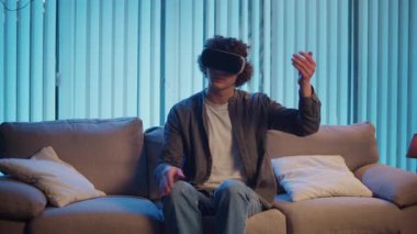 Genç Adam, AR Gözlükleriyle Sanal Arayüz 'le Gece Masasında Oturuyor. Yarının Dijital Dünyası 'nda etkileyici bir deneyim. Karışık Gerçeklik, Gelecek Teknolojisi, Zihinsel Kaçış.