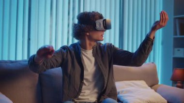 Genç Adam, AR Gözlükleriyle Sanal Arayüz 'le Gece Masasında Oturuyor. Yarının Dijital Dünyası 'nda etkileyici bir deneyim. Karışık Gerçeklik, Gelecek Teknolojisi, Zihinsel Kaçış.