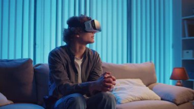 Genç Adam, AR Gözlükleriyle Sanal Arayüz 'le Gece Masasında Oturuyor. Yarının Dijital Dünyası 'nda etkileyici bir deneyim. Karışık Gerçeklik, Gelecek Teknolojisi, Zihinsel Kaçış.