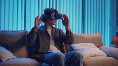 Genç Adam, AR Gözlükleriyle Sanal Arayüz 'le Gece Masasında Oturuyor. Yarının Dijital Dünyası 'nda etkileyici bir deneyim. Karışık Gerçeklik, Gelecek Teknolojisi, Zihinsel Kaçış.