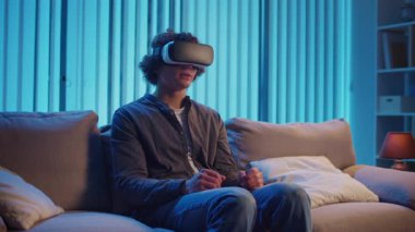 Genç Adam, AR Gözlükleriyle Sanal Arayüz 'le Gece Masasında Oturuyor. Yarının Dijital Dünyası 'nda etkileyici bir deneyim. Karışık Gerçeklik, Gelecek Teknolojisi, Zihinsel Kaçış.