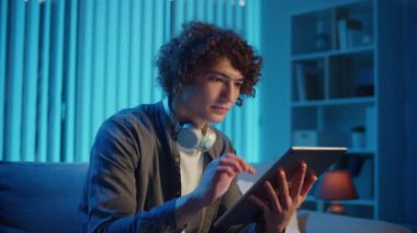 Man, Tablet Kullanarak Koltuğa Rahatlar, Muhtemelen Okuma ve Yayınlama İçeriğini İzler. Günlük Kişisel Bakım ve Dijital Çağ 'da Yavaş Yaşam. Dijital Detox, Akıl Sağlığı, Odaklanma Kipi.
