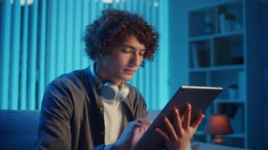 Man, Tablet Kullanarak Koltuğa Rahatlar, Muhtemelen Okuma ve Yayınlama İçeriğini İzler. Günlük Kişisel Bakım ve Dijital Çağ 'da Yavaş Yaşam. Dijital Detox, Akıl Sağlığı, Odaklanma Kipi.