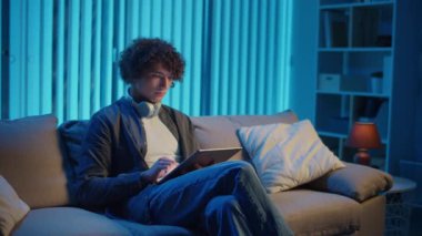 Man, Tablet Kullanarak Koltuğa Rahatlar, Muhtemelen Okuma ve Yayınlama İçeriğini İzler. Günlük Kişisel Bakım ve Dijital Çağ 'da Yavaş Yaşam. Dijital Detox, Akıl Sağlığı, Odaklanma Kipi.