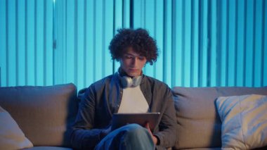 Man, Tablet Kullanarak Koltuğa Rahatlar, Muhtemelen Okuma ve Yayınlama İçeriğini İzler. Günlük Kişisel Bakım ve Dijital Çağ 'da Yavaş Yaşam. Dijital Detox, Akıl Sağlığı, Odaklanma Kipi.