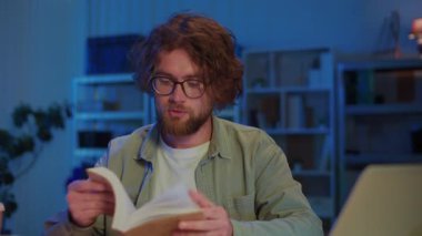 Genç Adam Kitap Okurken Akşam Çalışmalarına Odaklanıyor. Eğitim, Araştırma, Sınav Hazırlığı ve Ciddi Bilgiler Konsantrasyonuyla Akademik Adanmışlık.