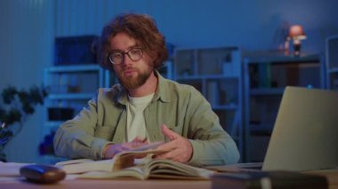 Genç Adam Kitap Okurken Akşam Çalışmalarına Odaklanıyor. Eğitim, Araştırma, Sınav Hazırlığı ve Ciddi Bilgiler Konsantrasyonuyla Akademik Adanmışlık.