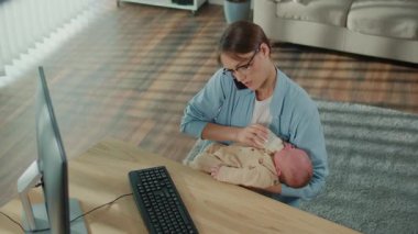 İş-Hayat Dengesi, Günlük Ebeveynlik, Hibrit Yaşam Tarzı. Modern Tarafsız Sahne 'de Profesyonel Bir Kadın Bebeğini Bir Şişeyle Beslerken Masasında Çalışıyor, Kariyer Görevlerini Dengelemekte ve Aile Bakımını Dengelemekte