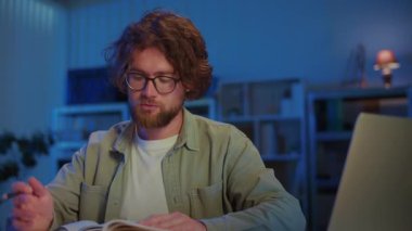 Genç Adam Kitap Okurken Akşam Çalışmalarına Odaklanıyor. Eğitim, Araştırma, Sınav Hazırlığı ve Ciddi Bilgiler Konsantrasyonuyla Akademik Adanmışlık.