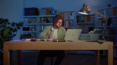 Sınav Hazırlığı. Genç bir erkek öğrenci, akademik baskı altında sıkı çalışmayı, odaklanmayı ve eğitime bağlılığı sembolize eden kitaplar ve bir dizüstü bilgisayarla gece geç saatlere kadar çalışır..