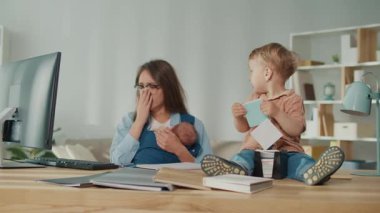 Günlük Ebeveynlik Gerçekliği. Bebekleri kucağında tutarken ve Bebeklere bakarken İç İşleri 'nden Çalışmak İçin Yorgun Anne Mücadelesi, Gerçek Ebeveynlik Zorlukları Gösteriyor