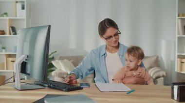 Aile dostu iş yeri. Genç Anne Kucağında Yürüyen Çocukla Uzaktan Çalışmayı Dengeleyerek, Ebeveynlerin Belirleyici ve Destekleyici İş Kültürünü Vurguluyor