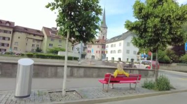 Chur şehrinin kırmızı bir bankında oturan bir kadın turistin arkası, İsviçre 'de antika bir kasaba. Brambruesch İsviçre kantonunun Chur başkenti.