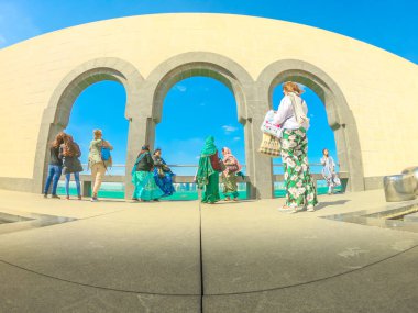 Doha, Katar - 5 Ocak 2019: İslami Sanatlar Müzesi 'nin avlusunun geniş açılı görüntüsü, Doha West Bay ufuk çizgisi ve Basra Körfezi üzerinde kemerli pencereler. Turistler popüler müzeyi ziyaret ediyorlar.