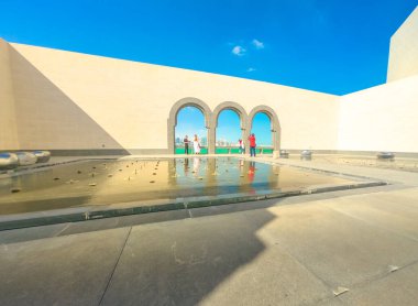 Doha, Katar-16 Şubat 2019: çeşme ile Islam Sanatı Müzesi avlusunda insanlar ve Doha West Bay ve Basra Körfezi üzerinde kemerli pencereleri açılış görünümü. Güneşli bir gökyüzü.