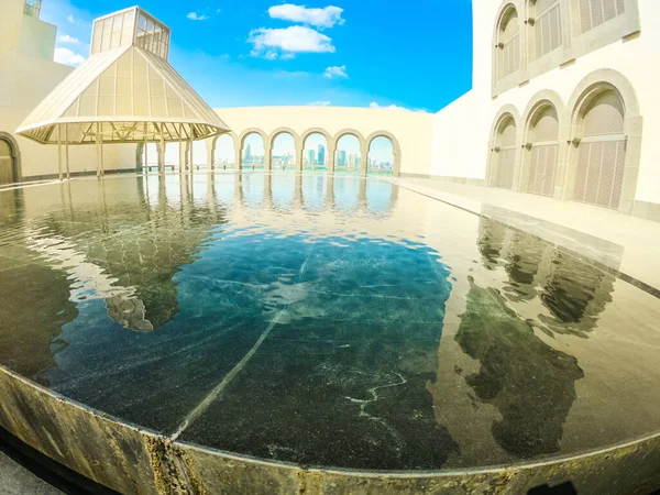 stock image Doha, Qatar - February 16, 2019: wide angle view of courtyard of Museum of Islamic Art with fountains and arched windows opening view on Doha West Bay and Persian Gulf reflecting in a pool.