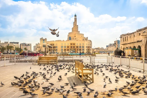stock image Doha, Qatar - February 20, 2019: Many pigeons flying in Souq Waqif in front of Fanar Islamic Cultural Center with Mosque and Minaret on background. Middle East, Arabian Peninsula, Persian Gulf.