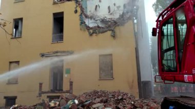 Bir inşaat sahasında mekanik kazıcılı bir yapının tahrip edilmesi ve bir konutun restorasyonu. İnşaat endüstrisi, matkapla duvarları yıkmak için buldozer kullanan işçilerle dolu..