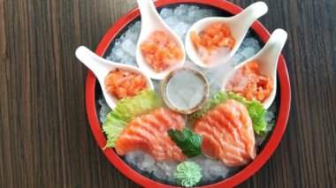Çiğ somon balığı dilimleri Japon mutfağı moda restoranı. Ahşap bir masada zencefil, wasabi ve sebzelerle birlikte somon balıklı saşimi yemeğinin üst görüntüsü. Kuru buz tüten Japon yemeği..