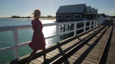 Peşimden Busselton jetty Busselton Town, Batı Avustralya üzerinde kırmızı yürüme sarışın kadın. Kadın turist Gezgin, WA, Avustralya ikonik ahşap iskele yolculuğun kavramı