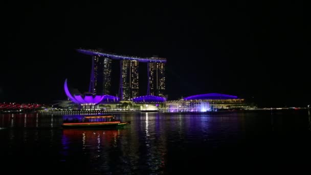 シンガポール 2018年4月27日 マリーナベイを横断するフェリーは シンガポールのマリーナベイのウォーターフロント遊歩道にあるArtscience MuseumのそばにあるSands Hotel Casinoによる夜のレーザーショーでマリーナベイを横断します — ストック動画