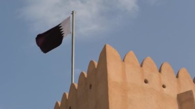 Details of arabian castle tower with Qatar flag in Doha city of Middle East in Persian Gulf. Famous tourist attraction.