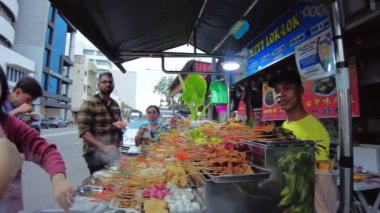 George Town, Malezya - Jan 2023: Popüler Penang lezzetleriyle Jetty 'yi çiğne. Ziyaretçiler, ahşap kaldırımlarda otururken nefes kesen deniz manzaralı evlerin yanında yiyecek tadabiliyorlar..