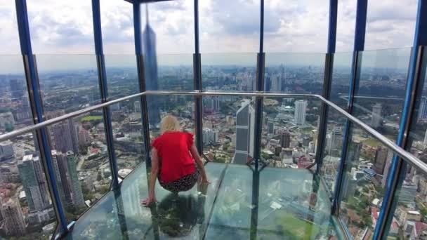 女人在吉隆坡的周围看到美丽 就会带来现代性和繁荣 周围环绕着城市的天际和城市的声音 她脚下的玻璃杯和她皮肤上温暖的阳光 — 图库视频影像