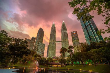 Kuala Lumpur, Malezya - Ocak 2023: Petronas İkiz Kuleleri, parlak renkler ve çarpıcı bir ışık gösterisi ile gün batımı gökyüzünü aydınlatıyor.