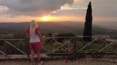 Tuscany 'nin İtalya kırsalındaki Toskana şarapçı köyünde gün batımını seyreden bir kadın. İtalya 'nın şarap bölgesinin bağları. Gün batımında İtalya 'nın Toskana bölgesi.