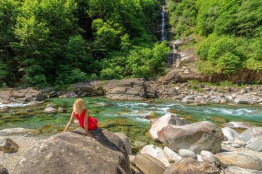 Kırmızılı zarif bayan Verzasca nehrinde. Lavertezzo kasabasındaki Verzasca vadisi. Ticino, İsviçre 'de Riverside eğlence ve yüksek dalış yeri.