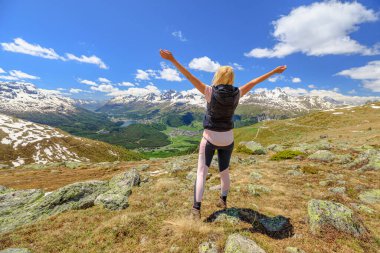 Günbatımında turist kadın İsviçre 'de Muottas Muragl' ın tepesinde yürüyüş yapıyor. İsviçre 'nin Graubunden kantonunda popüler dağ gezileri.
