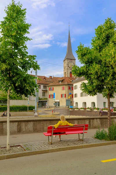 Chur şehrinin kırmızı bir bankında oturan bir kadın turistin arkası, İsviçre 'de antika bir kasaba. Brambruesch İsviçre kantonunun Chur başkenti.