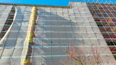 İnşaat sırasında yapı inşaatı için iskele. Ev yenileme çalışmaları için kullanılıyor ve işçiler için bir çalışma platformu sağlıyor. Bu bir yapı iskelesinin ön görüntüsü..