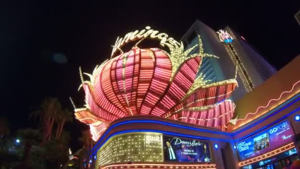 美国内华达州拉斯维加斯 2018年8月 夜间时分 拉斯维加斯的火烈鸟赌场变得热闹起来 其标志性的粉色火烈鸟标志闪烁着光芒 繁忙的操场挤满了人群 — 图库视频影像