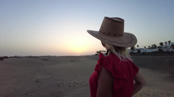 戴太阳帽的女游客来遮挡日落 她闭上眼睛 倾听远方海浪的声音 或看着沙丘在微风中移动和改变形状 — 图库视频影像
