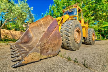 Ağır ve güçlü sarı buldozer kazıcısının geniş açı ve perspektif görüntüsü bir yol inşaatı için tekerlekler üzerinde. Çalışmalar devam ediyor, endüstriyel makine.