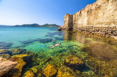 Kayaların etrafında Methoni Castle, Methoni bağlantı noktası, Messinia, Peloponnese, Yunanistan için bir Ortaçağ surlarının içinde şnorkel kadın bikini. Kadın snorkeler kristal suda yüzüyor. Yaz su sporları etkinliği