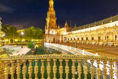 Seville, Endülüs, İspanya 'daki Plaza de Espana' daki Rönesans yapısı Guadalquivir nehrinin akan sularını güzel bir şekilde yansıtır. İspanya Meydanı, geceleri büyüleyici ışıklarla bezenmiş..