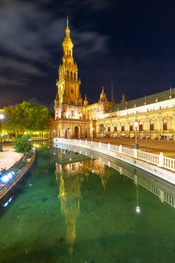 Sevilla, Endülüs, İspanya 'daki Plaza de Espana' da bulunan Rönesans yapısı Guadalquivir nehrinin çarpıcı bir yansımasıdır. İspanya Meydanı, gece aydınlatıldığında büyüleyici ve büyüleyici bir yerdir..