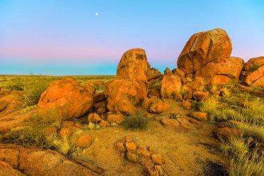 Şeytani Mermerleri Koruma Alanı 'ndan pembe renkli alacakaranlık gökyüzü ile inanılmaz doğal manzaralar. Orta Avustralya 'daki Kuzey Toprakları, Avustralya taşrasının granit kayalar sembolü.