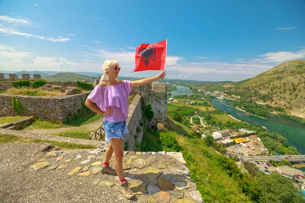 Woman with Albanian flag on Rozafa castle in Albania. The castle offers stunning panoramic views of the surrounding landscape, the Buna, Drin, and Kir rivers.