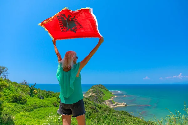 Woman with Albanian flag on Cape of Rodon in Albania. The tranquil beaches along the cape provide opportunities for relaxation, swimming, and sunbathing.