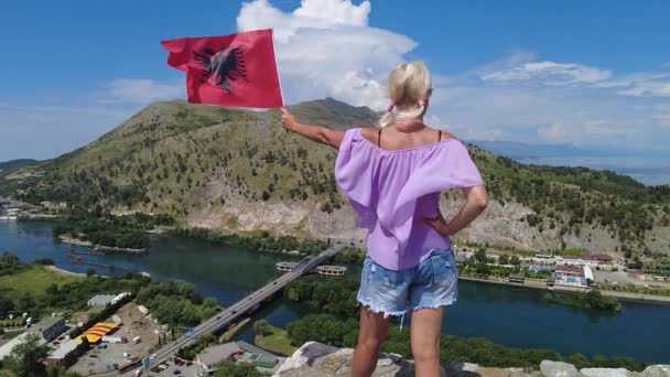 アルバニアのロザファ城にアルバニア国旗を掲げた女性 城は周囲の風景 ヴァイナ ドリン キル川の素晴らしいパノラマビューを提供しています — ストック動画
