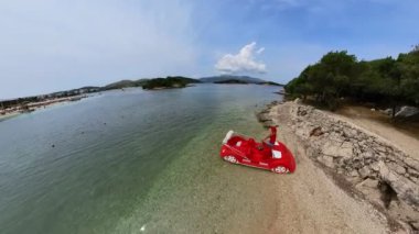 Arnavutluk 'un Ksamil takımadasında, insanların sahili keşfetmek için karaya çıktığı Ishul Ksamil Adası' nın kumlu kıyılarına giden bir pedal gezisindeki bir kadının insansız hava aracı görüntüsü.