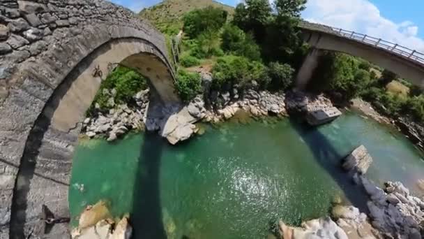 アルバニアに位置するメシ橋のドローンビューは メシの絵のように美しい村でキール川にまたがる建築の宝石です この歴史的な石造りの橋は オスマン時代にまで遡る — ストック動画
