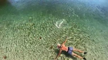 Ksamil Adaları sahilinde yüzen bir kadının drone görüntüsü. Ksamil farklı bir ortam ve cazibe sunarak, ziyaretçilere yakın çevrede çeşitli doğal harikalar yaşama şansı sunuyor.