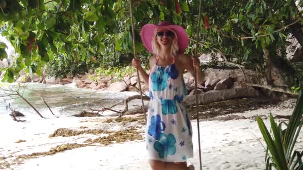 スローモーション ラディグ セーシェル インド洋のアンセセセビアのトロピカルツリーの下でスイングで帽子を持つかなり観光客の女性 夏休みで楽しむライフスタイルの女性 — ストック動画